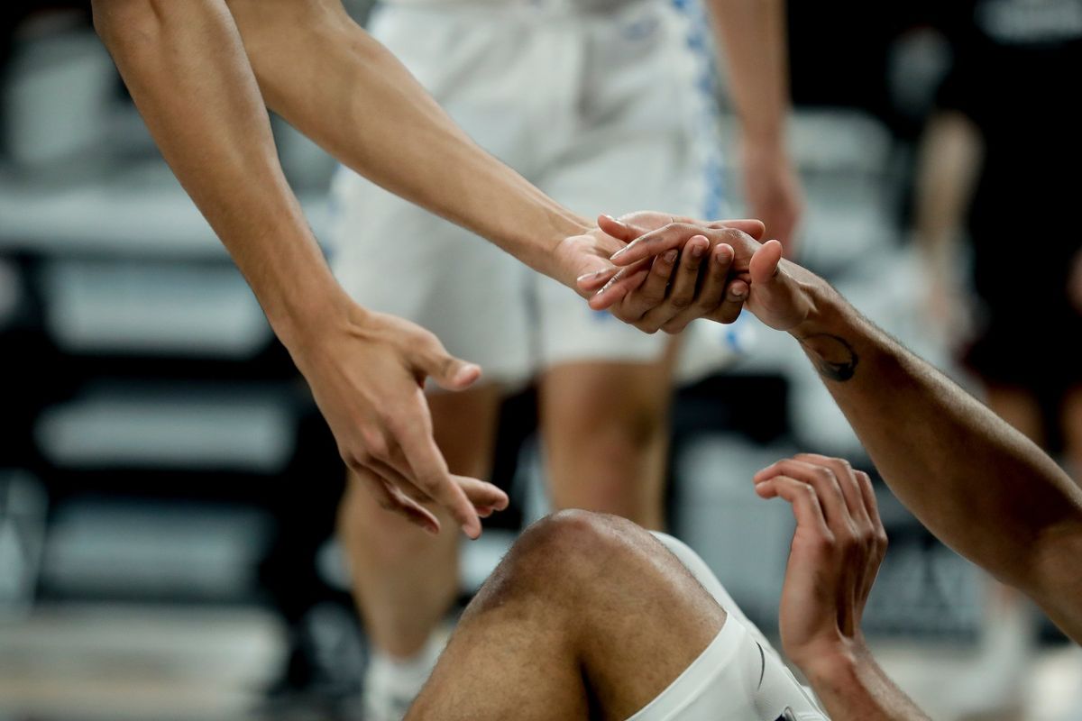 A basketball player helping a teammate to their feet